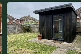 Dark garden studio with a glass door and sloping roof