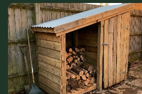 Open-front wooden shelter filled with stacked firewood